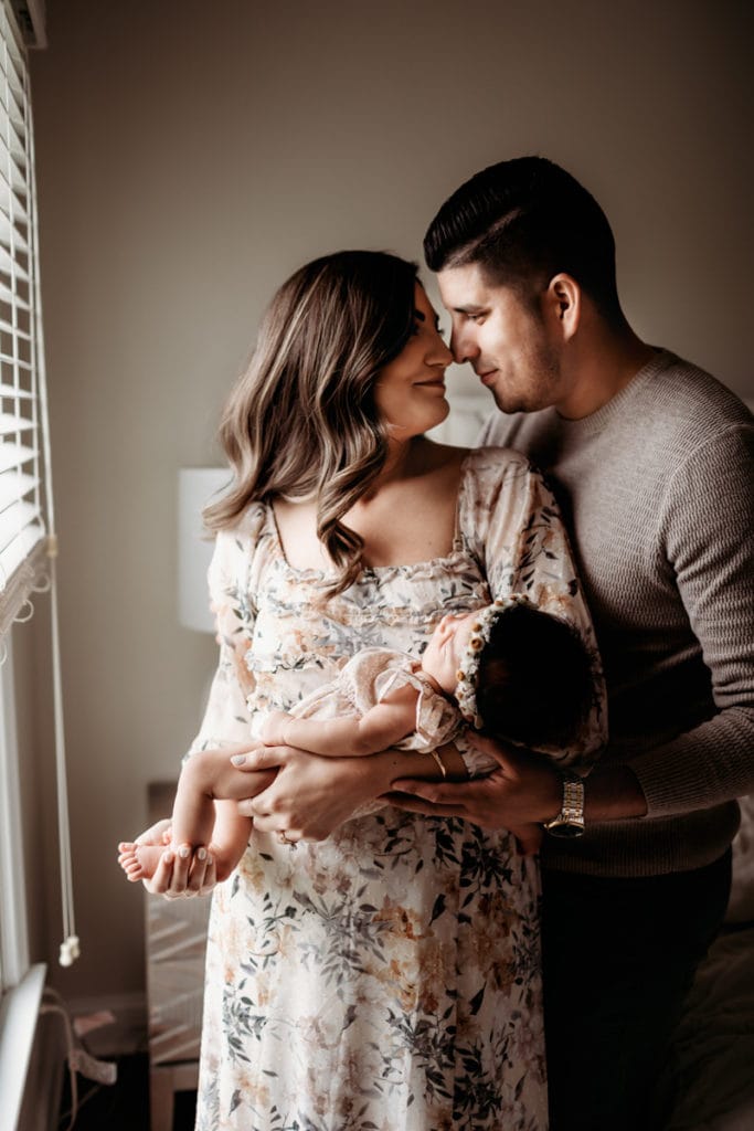 Newborn Photographer, Mom and dad draw close, nose to nose, mother holds baby