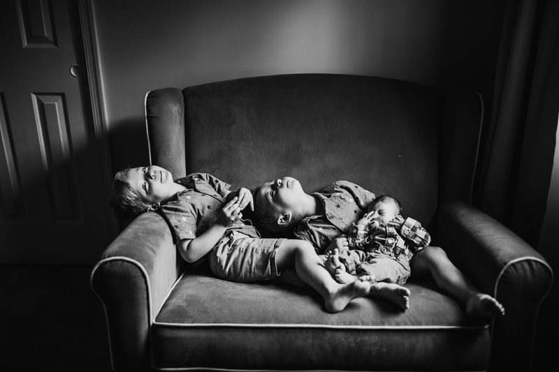 Family Photographer, two siblings rest on each other in the living room on the couch
