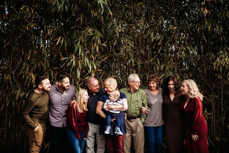 Famiy Photographer, a large extended family admires each other, huddled together and smiling, grandparents and their children and grandchildren