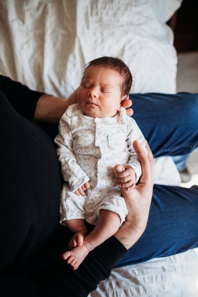 Newborn Photographer, a baby being held in moms lap sleeps soundly