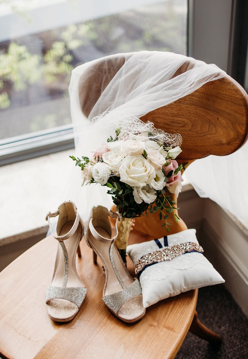 Wedding Photographer, shoes and wedding bouquet sit on a chair in preparation for the day