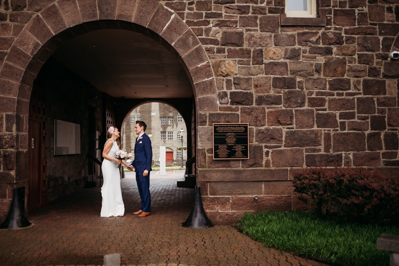 Wedding Photographer, bride and groom smile together beneath park tunnel