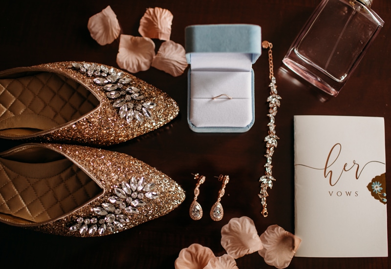 Wedding Photographer, shoes, earrings, vows, rings, and perfume sit on a table