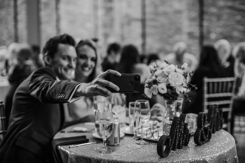 Wedding Photographer, the groom takes a selfie of he and his wife together at their reception