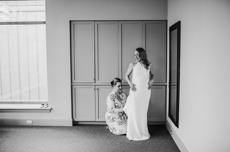 Wedding Photographer, a woman helps the bride with her wedding dress