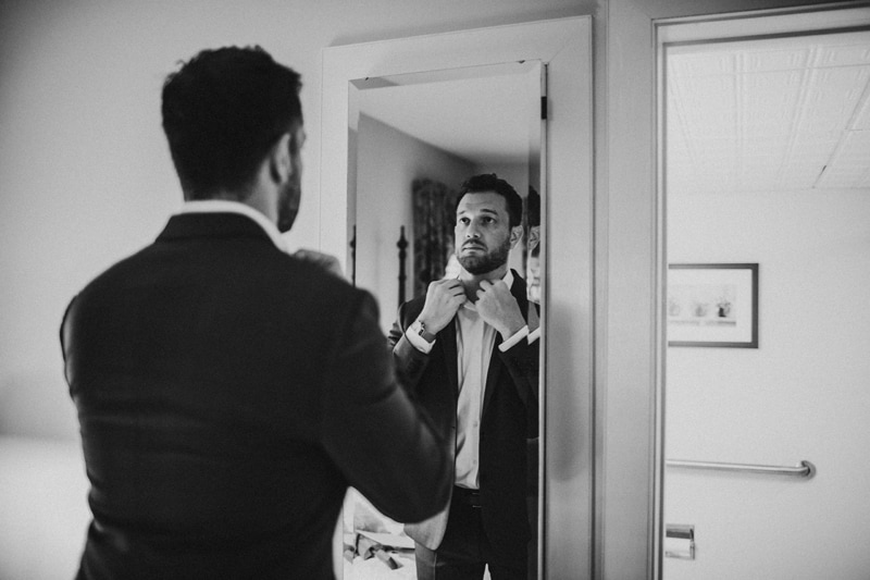 Wedding Photographer, a man adjusts his shirt within his suit