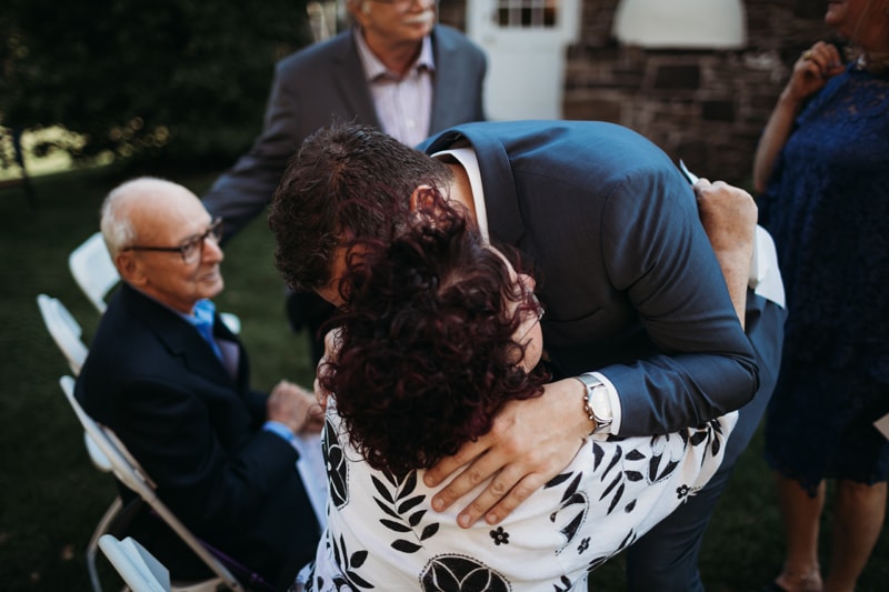 Wedding Photographer, the groom hugs his grandmother, his grandfather looks on proudly
