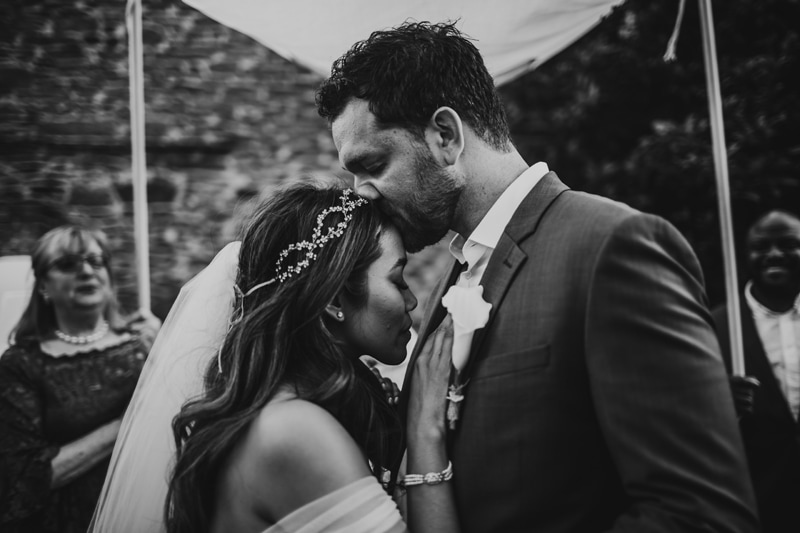 Wedding Photographer, groom kisses bride on the forehead at wedding ceremony