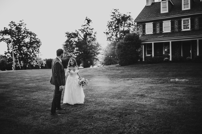 Wedding Photographer, in their suit and wedding dress, now husband and wife walk on estate lawn