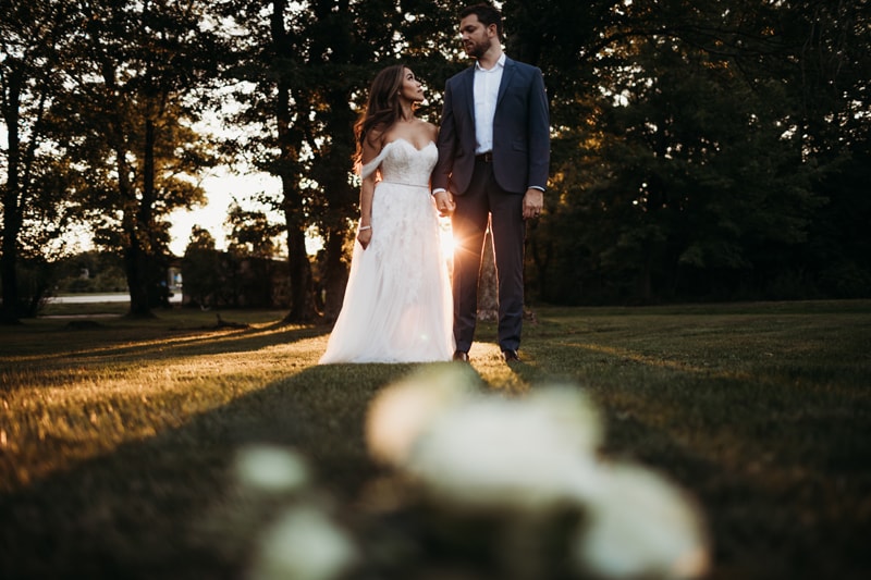 Wedding Photographer, bride and groom look at each other, holding hands at golden hour