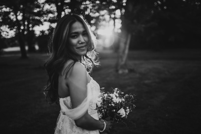 Wedding Photographer, a bride looks happy holding flowers in the park