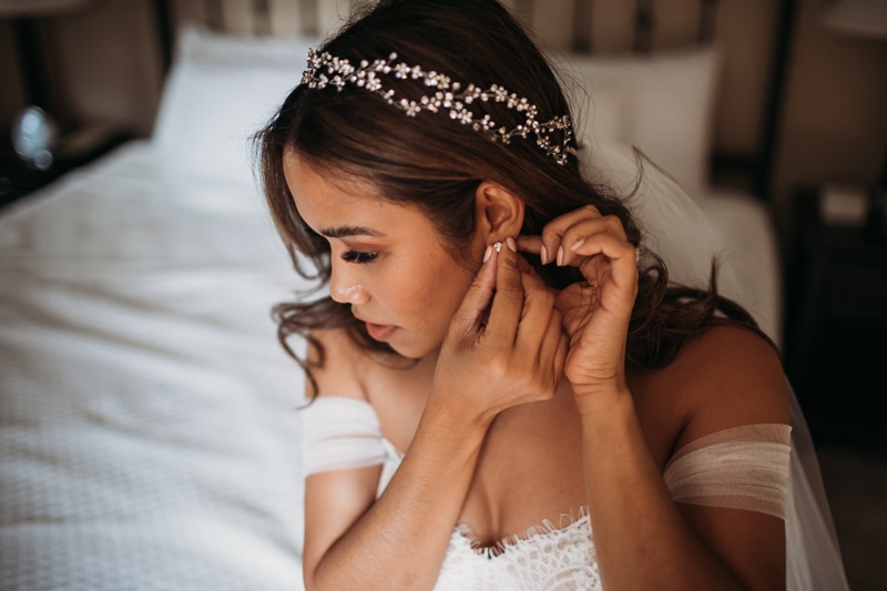 Wedding Photographer, a bride puts on her earrings