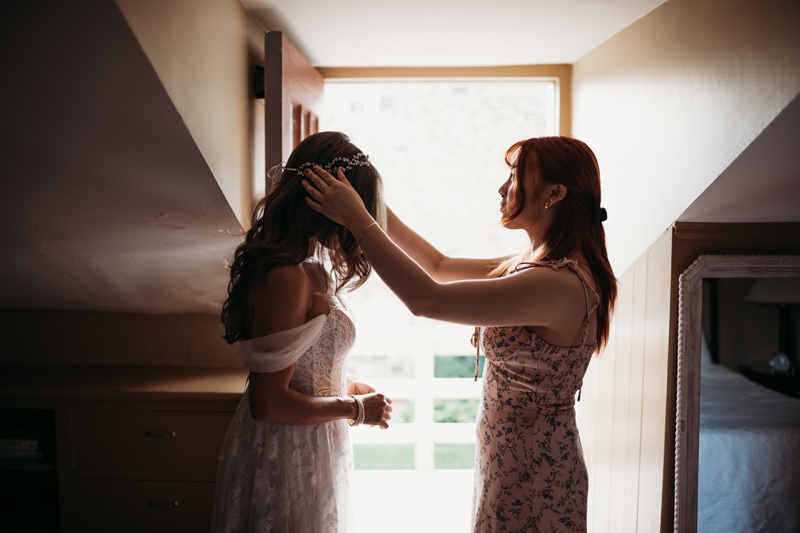 Wedding Photographer, a woman helps put a crown on a bride