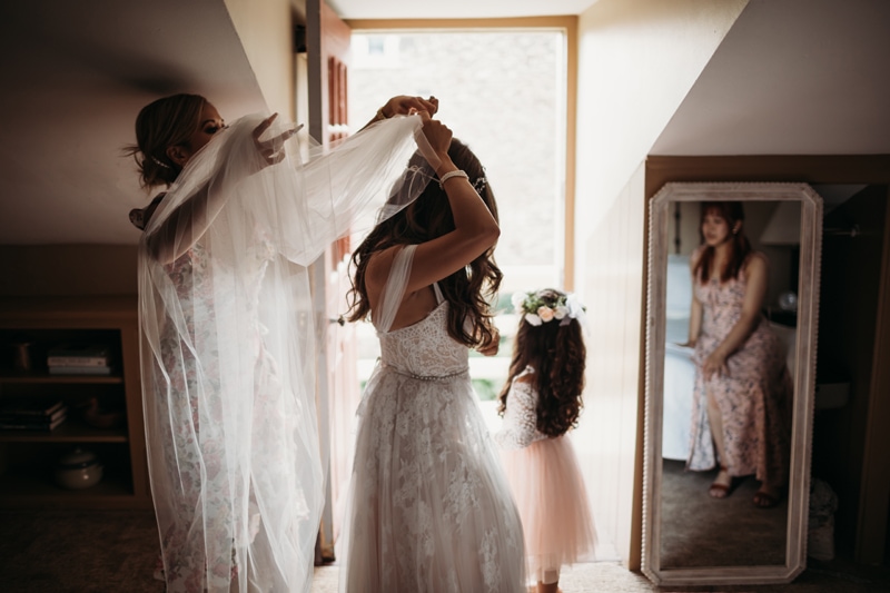 Wedding Photographer, a bridesmaid assists the bride with her veil