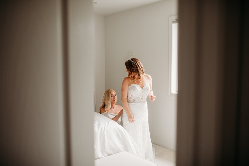Wedding Photographer, a mother helps her daughter with her wedding dress