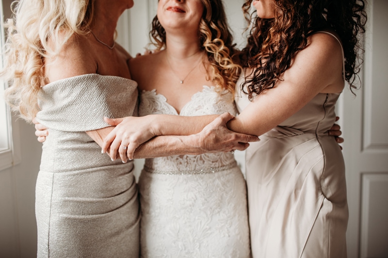 Wedding Photographer, a bride and her bridesmaid embrace