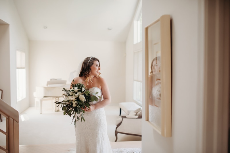 Wedding Photographer, a bride stands in her home with a bouquet and wedding dress on