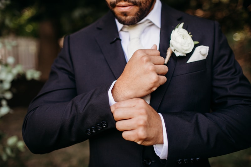 Wedding Photographer, a groom adjusts his shirt cuffs beneath his suit