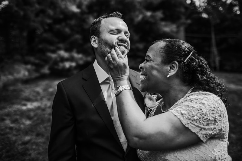 Wedding Photographer, a groom's mother pinches his cheeks in excitement for the big day