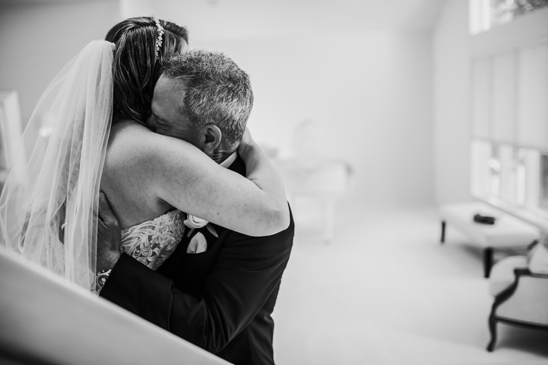 Wedding Photographer, a bride and her father embrace in their home