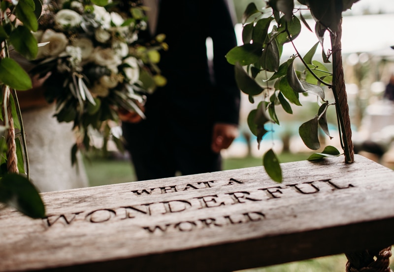 Wedding Photographer, a bride and groom stand before a swing in the garden that reads "What a wonderful world"
