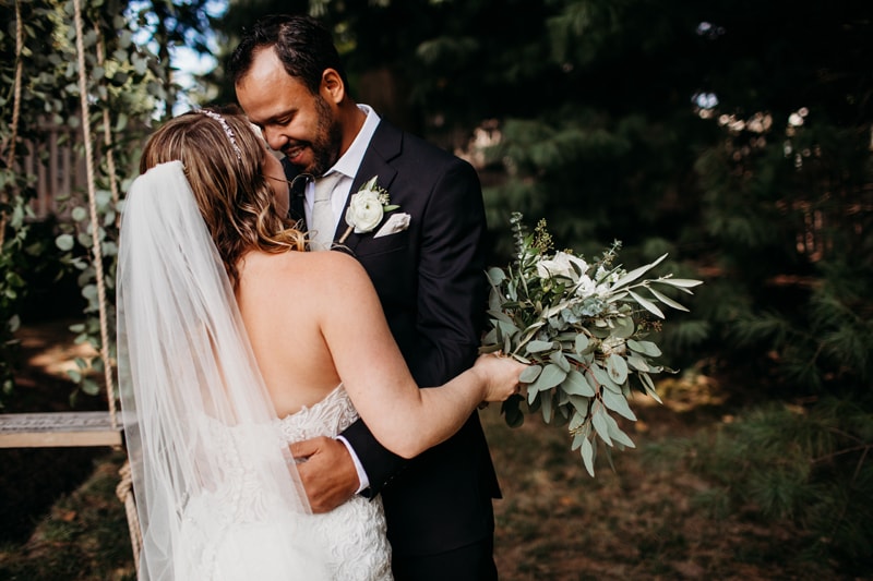 Wedding Photographer, bride and groom embrace in their yard