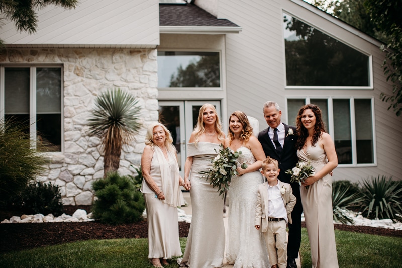 Wedding Photographer, the bride stands with her family before their home