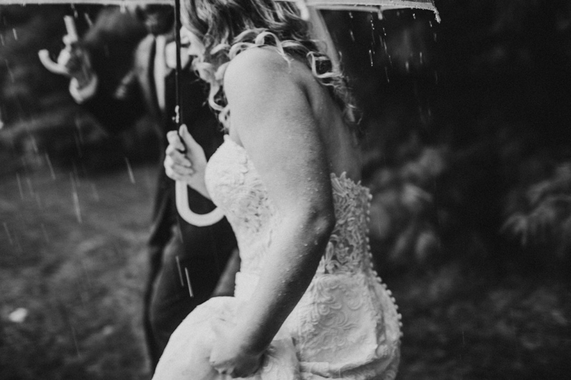 Wedding Photographer, bride and groom walk beneath umbrellas