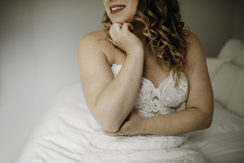 Wedding Photographer, a woman sits on her bed in her wedding dress