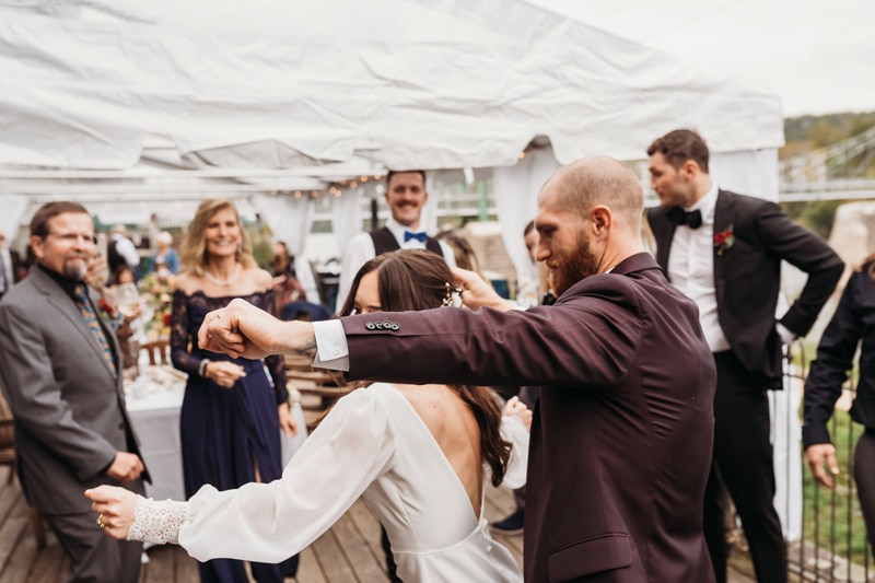 Wedding Photographer, the bride and groom dance together as other look on and smile